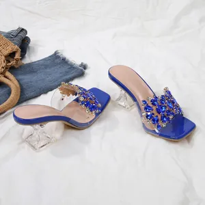 Detail van blauwe strass slippers met kristallen hakken en een moderne vierkante neus.