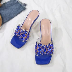 Detailweergave van blauwe strass slippers met kristallen hakken en transparante bandjes