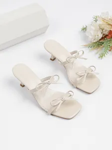 Detailansicht eleganter beiger Pantoletten mit Kitten-Heel, Schleifen und Karree-Spitze