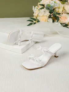 Elegante weiße Pantoletten mit Pfennigabsatz, eckiger Zehenpartie und Schleifen-Details