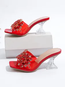 Detail van rode muiltjes met strass en transparante kristallen hakken.