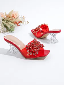 Close-up van elegante rode mules met strassteentjes en transparante kristallen hakken