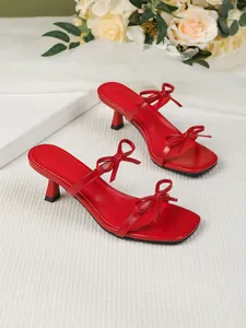 Elegante rote Sandalen mit Pfennigabsatz, Karree-Zehenpartie und Schleifendetails.