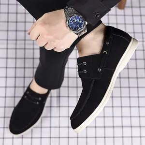 Detail view of black suede men's loafers worn with casual black trousers and watch.