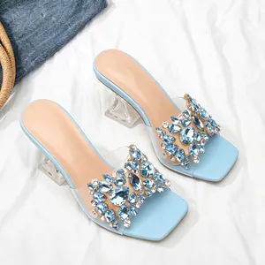 Close-up van lichtblauwe sandalen met blauwe steentjes en een kristalheldere hak