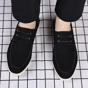 Top view of black minimalist men's loafers with white sole on a grid background.