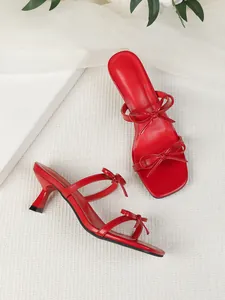 Elegante rote Sandaletten mit Pfennigabsatz, eckiger Zehenpartie und Schleifendetails.