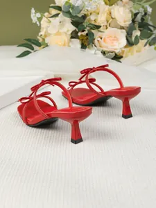Detailansicht roter Kitten-Heel-Sandalen mit eleganten Schleifenakzenten und eckiger Zehe.