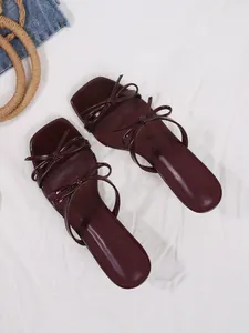 Draufsicht auf burgunderrote Sandalen mit Pfennigabsatz und eleganten Schleifendetails.