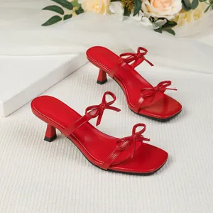 Elegantes sandalias rojas de tacón bajo con punta cuadrada y detalles de lazos.