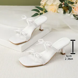 Elegantes sandalias blancas de tacón bajo con punta cuadrada y detalles de lazos