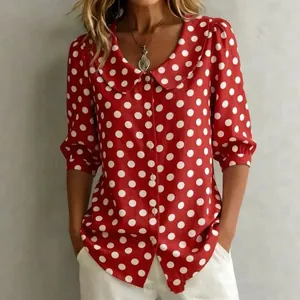 Détail de chemisier rouge à pois blancs avec col Claudine et manches bouffantes.