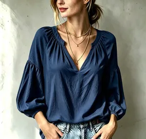 Gros plan d'une blouse bleue à col en V avec détails plissés et manches lanternes.