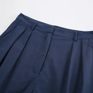 Detail shot of navy blue cotton linen trousers showing waist pleats and belt loops