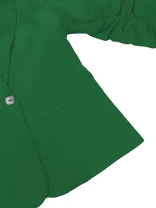 Détail d'un blazer vert pour femme avec bouton perlé et manches plissées