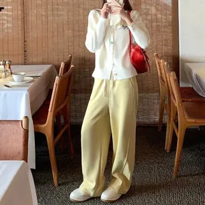 Woman wearing white knit cardigan with colorful buttons and dog embroidery in a cafe