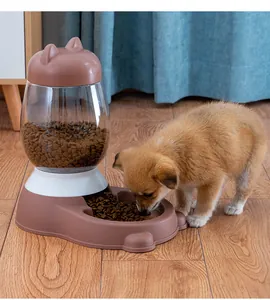 Small puppy eating kibble from an automatic gravity pet feeder on a wooden floor