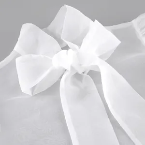 Primer plano de blusa de malla transparente blanca con un gran lazo elegante al cuello