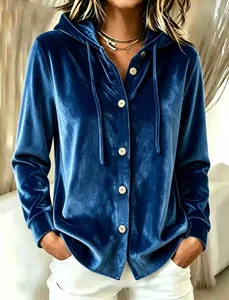 Gros plan d'un cardigan à capuche en velours bleu avec des boutons blancs et doux.