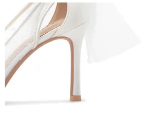 Close-up of white bridal stiletto heel with polka dot mesh and sheer tulle bow detail.