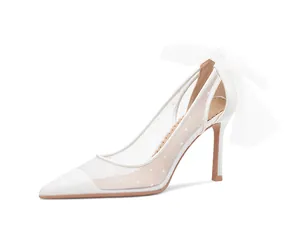 Detailed side view of elegant white pointed toe pump with mesh polka dots and bow