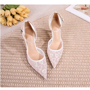 Gros plan de chaussures de mariage en dentelle blanche avec broderie de motifs cœurs
