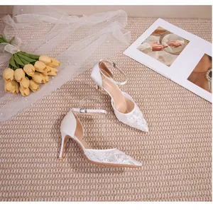 Escarpins de mariée élégants en dentelle blanche avec bride cheville, présentés avec tulipes