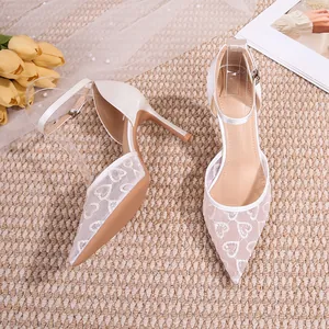 Détail des chaussures de mariée blanches avec dentelle brodée de cœurs fins