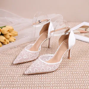 Détail de chaussures de mariage en maille de dentelle blanche avec broderie cœur