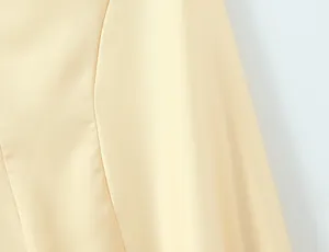 Close-up view of the smooth light yellow fabric texture of a summer backless dress.