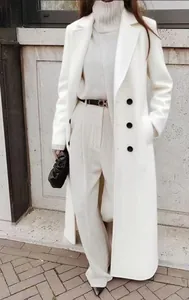 Close-up of elegant long white woolen coat styled with beige sweater and trousers