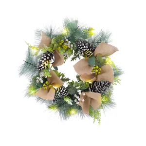 Beleuchteter Weihnachtskranz mit Zapfen, Beeren und Juteschleifen für die Feiertage