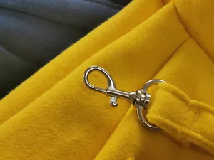 Close-up of durable metal swivel clasp and yellow fabric strap on pet carrier backpack