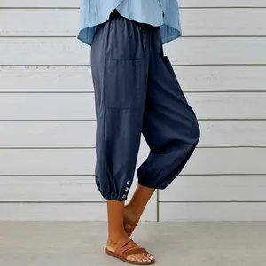 Detail view of casual navy blue linen cropped pants with drawstring and buttoned cuffs.