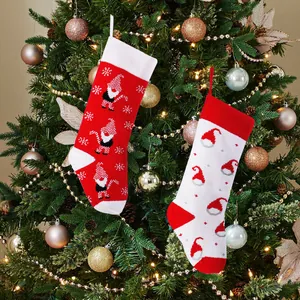 Festive set of two red and white knitted Christmas stockings on a decorated tree.