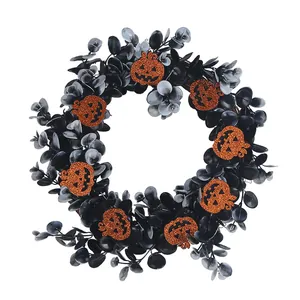Halloween wreath with black eucalyptus leaves and orange glitter pumpkins for door decor