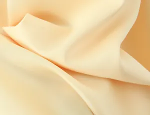 Close-up view of elegant smooth pale yellow fabric showing soft folds and matte texture