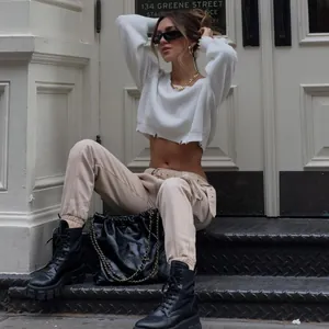 Chic white cropped knit sweater featuring a distressed hem in a street style setting.
