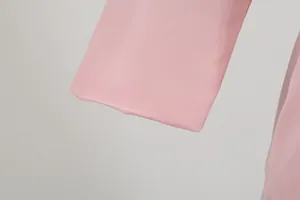 Close-up of pink blazer sleeve showing fine twill fabric texture and clean hem.
