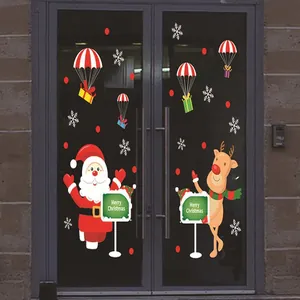 Primer plano de pegatinas navideñas con Papá Noel y renos en una puerta de cristal oscuro