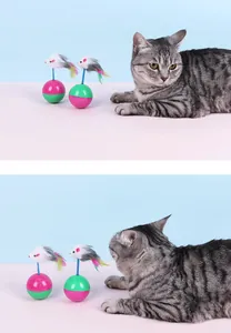 Grey tabby cat interacting with colorful tumbler toys featuring plush mice and feathers
