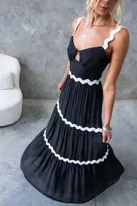 Détail d'une robe midi noire à volants avec bordure ondulée blanche et décolleté cœur