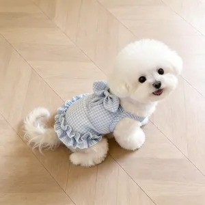 Detailed view of blue gingham pet dress featuring elegant ruffles and a bow on a white dog