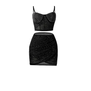 Vista detallada de un conjunto de dos piezas negro con brillantes, top corto y falda cruzada.