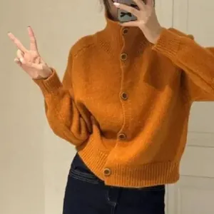 Primer plano de una chaqueta de punto naranja vibrante con cuello alto y botones marrones