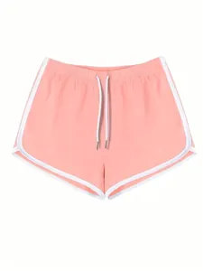 Dettaglio frontale dei pantaloncini sportivi rosa da donna con profili bianchi.