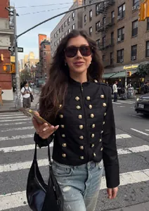 Veste courte noire style rétro britannique avec col montant et boutons dorés en ville.
