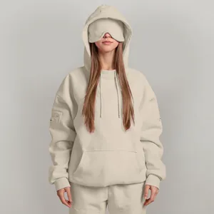 Detail view of a beige oversized hoodie with a unique built-in eye mask for sleeping.