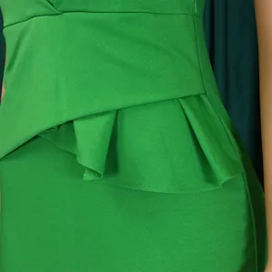 Detailansicht des eleganten grünen Kleides mit Rüschendesign an der Taille und Stoffstruktur.