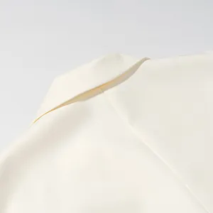 Close-up of elegant cream blazer collar detailing fine fabric texture and stitching.